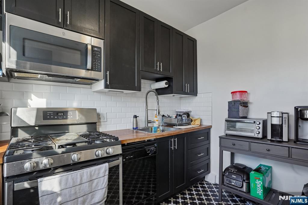 82 Hackensack Street, Unit 6 Wood-Ridge, NJ 07075 - Photo 10 of 28 a kitchen with stainless steel appliances a stove a sink dishwasher and cabinets with wooden floor