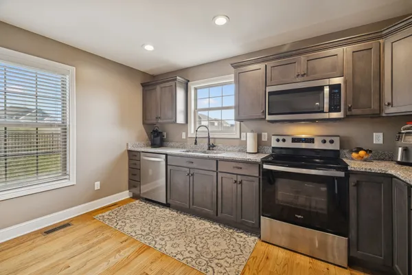 a kitchen with stainless steel appliances granite countertop a stove a sink and a microwave