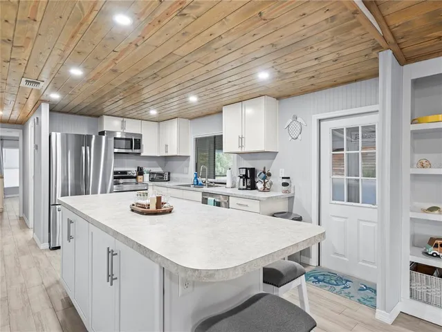 a kitchen that has a lot of cabinets a sink and appliances