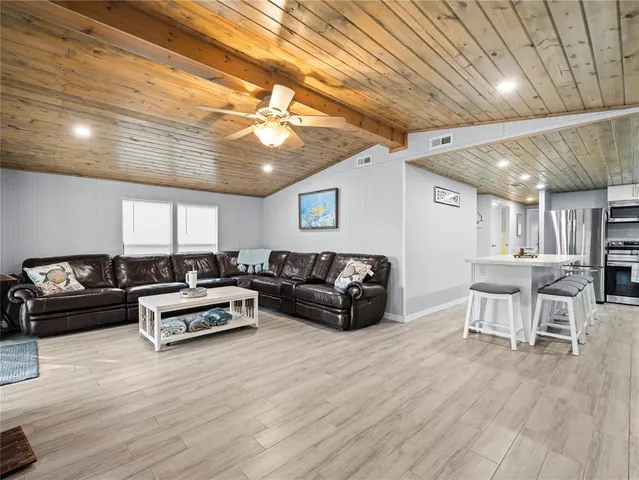 a kitchen with stainless steel appliances granite countertop a kitchen island a stove a sink a dining table and chairs with wooden floor