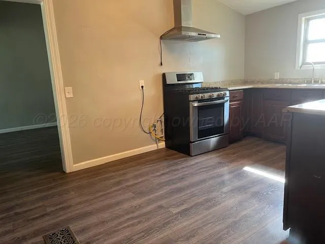 a kitchen with granite countertop a stove and a wooden floor