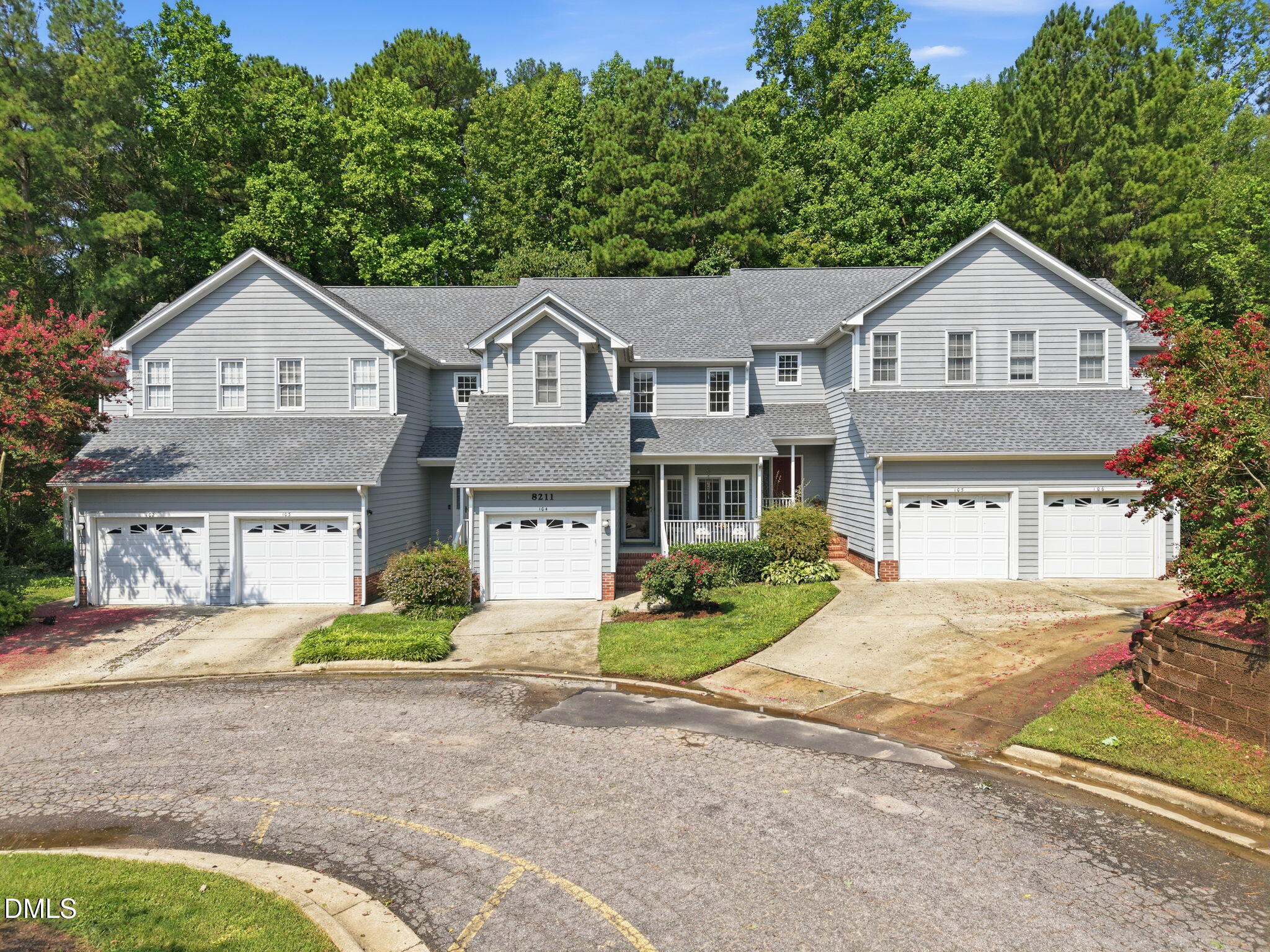 8211 Hempshire Place, Unit 104 Raleigh, NC 27613 - Photo 32 of 34 Gray siding exterior with multiple pitched roofs, individual garages, and a prominent front entrance with a covered porch