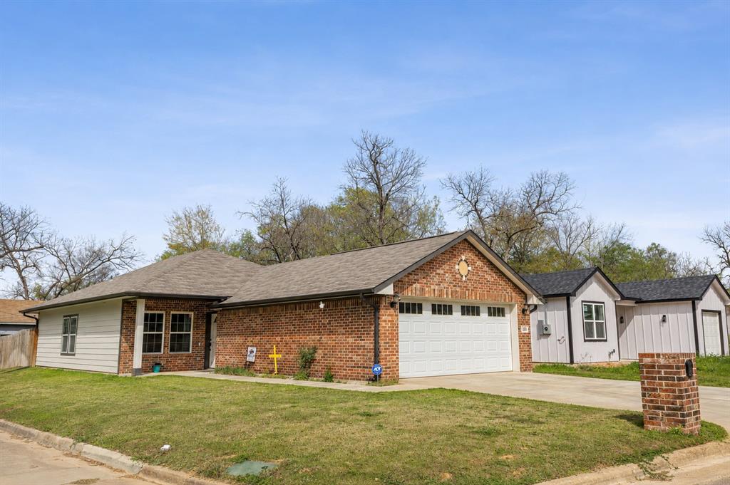 101 Ross Street Sulphur Springs, TX 75482 - Photo 1 of 30 Brick and siding exterior featuring a two-car garage with a white sectional door, a concrete driveway, and a shingle roof