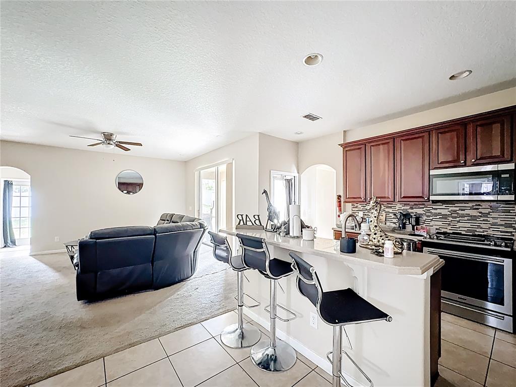 1692 Scrub Jay Road Apopka, FL 32703 - Photo 20 of 35 a living room with stainless steel appliances kitchen island granite countertop a table and chairs in it