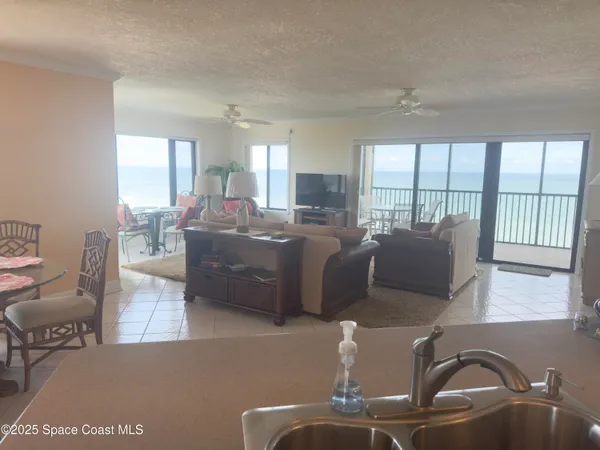 a living room with furniture two large windows and a dining table