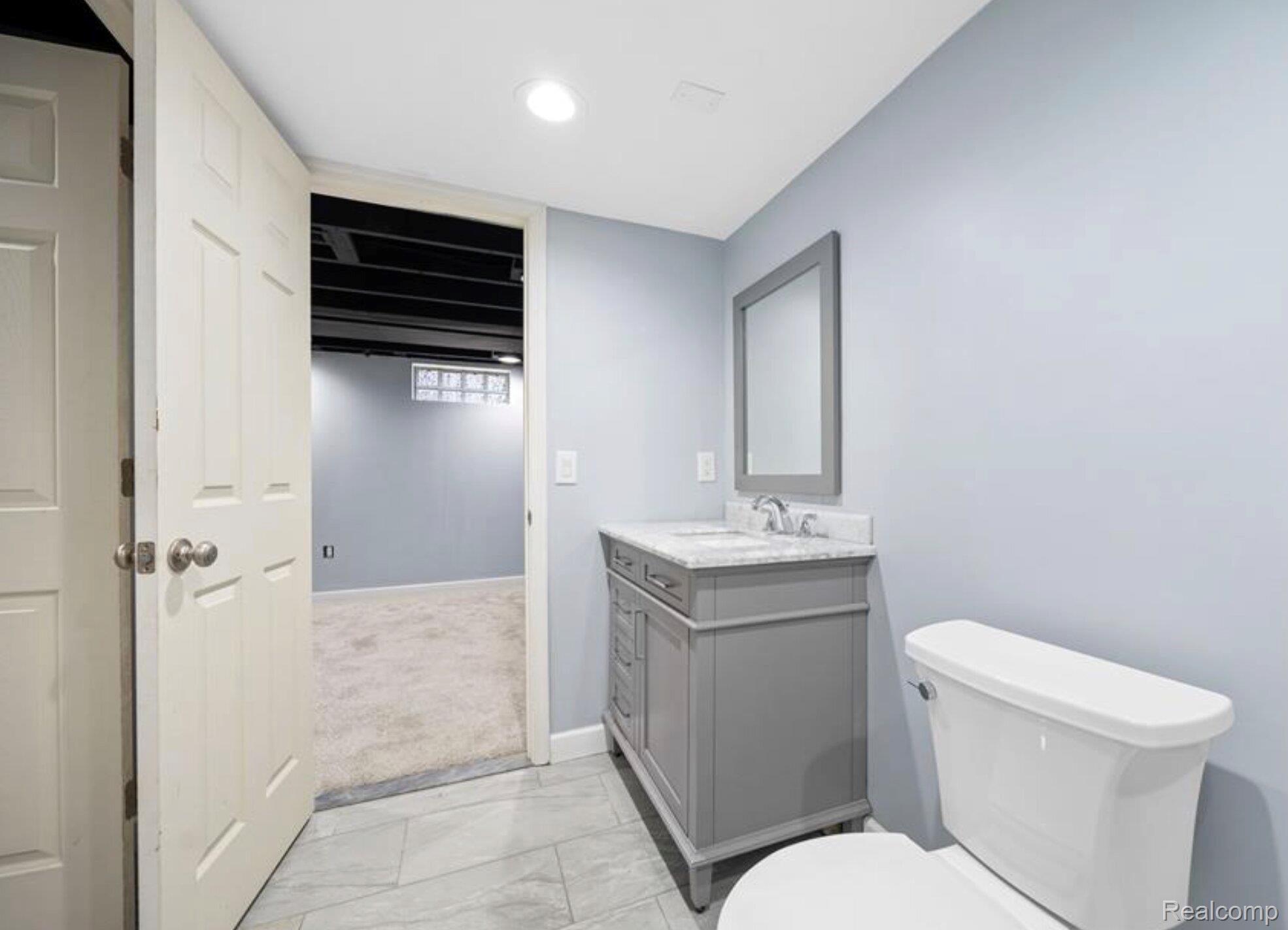 4214 Berkshire Road Royal Oak, MI 48073 - Photo 20 of 27 Bathroom featuring a single vanity with a marble-finish countertop, gray cabinetry, and a framed mirror