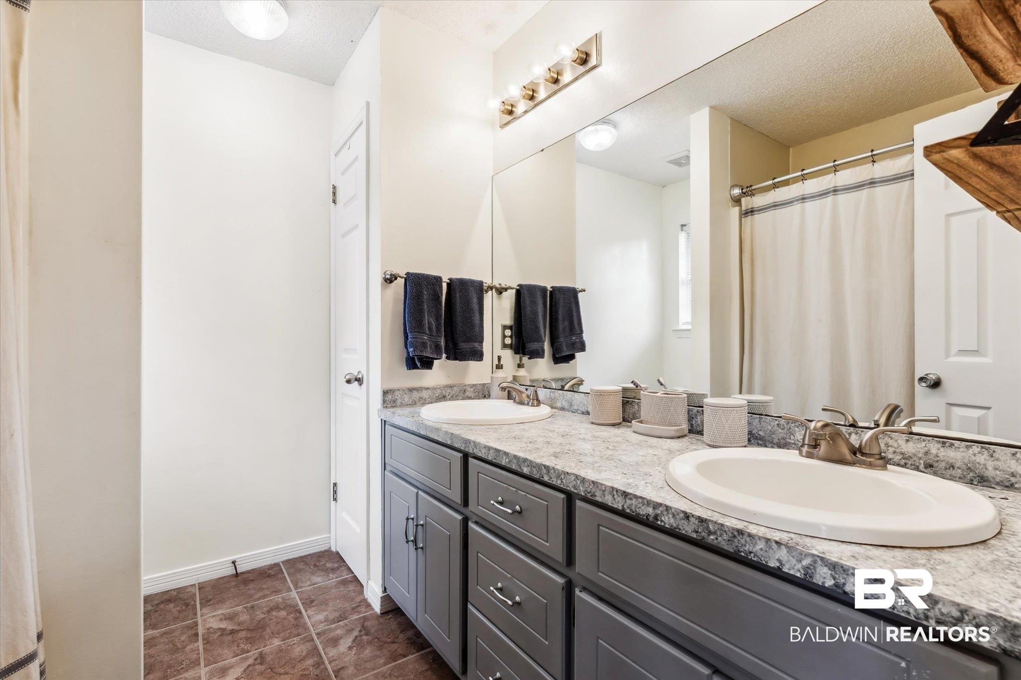 9306 Prairie Drive Semmes, AL 36575 - Photo 10 of 20 Bathroom with dual vanity, tile patterned floors, and a textured ceiling