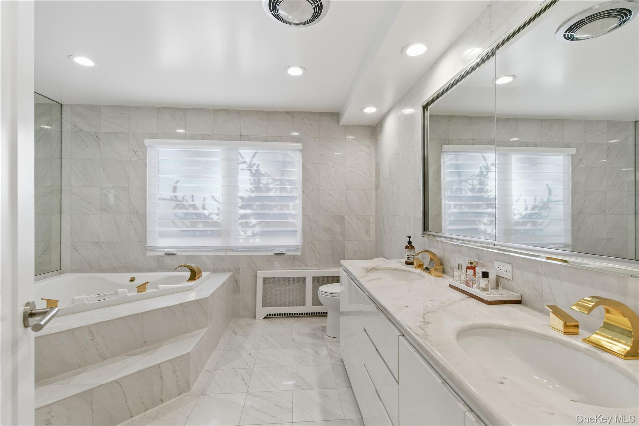 108 Bacon Road Old Westbury, NY 11568 - Photo 18 of 39 a bathroom with a granite countertop tub a double vanity sink a toilet and a large mirror