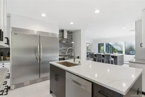 a kitchen with stainless steel appliances granite countertop a sink a refrigerator and a refrigerator