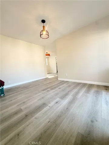 a view of an empty room with wooden floor and fan