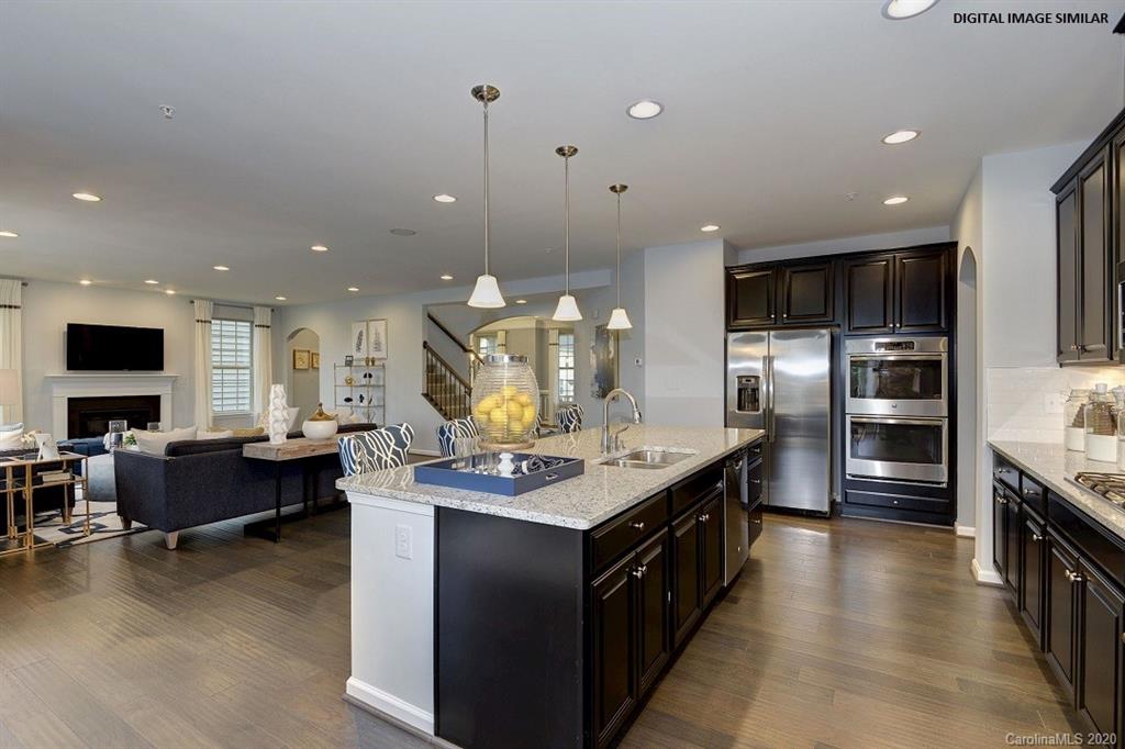 7111 Messina Road, Unit 128 Indian Land, SC 29707 - Photo 3 of 15 a kitchen with stainless steel appliances kitchen island granite countertop a stove and a sink