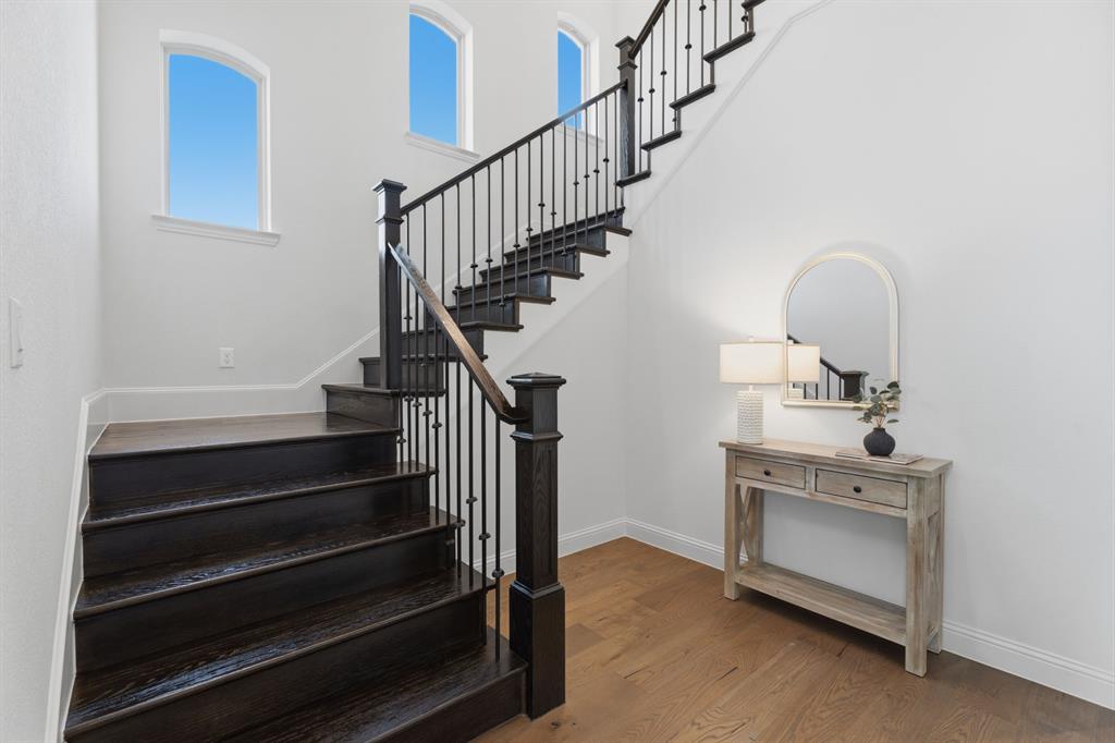 1316 Limestone Ridge Road Mansfield, TX 76063 - Photo 26 of 40 Grand staircase featuring dark wood-finish treads and risers with a black wrought iron baluster system