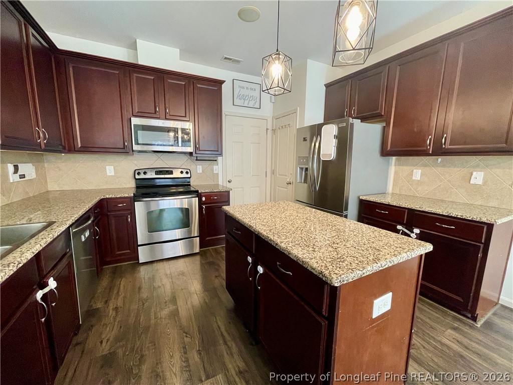 144 Bicentennial Way Cameron, NC 28326 - Photo 7 of 23 a kitchen with stainless steel appliances granite countertop wooden cabinets a stove top oven a sink and dishwasher