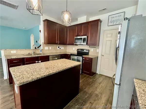 a kitchen with stainless steel appliances granite countertop wooden cabinets a refrigerator a stove a sink and dishwasher