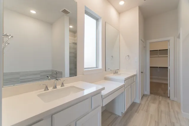 a bathroom with a sink double vanity granite tub shower and a mirror