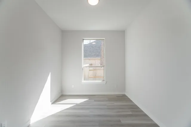a view of an empty room with wooden floor and closet