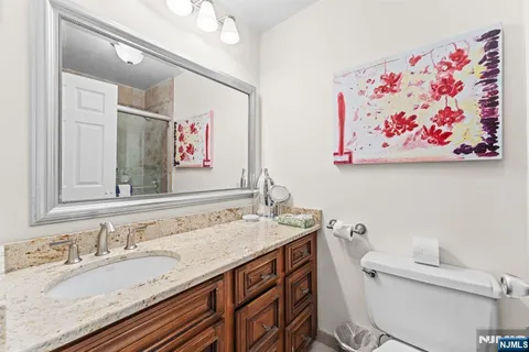 a bathroom with a granite countertop sink mirror and toilet