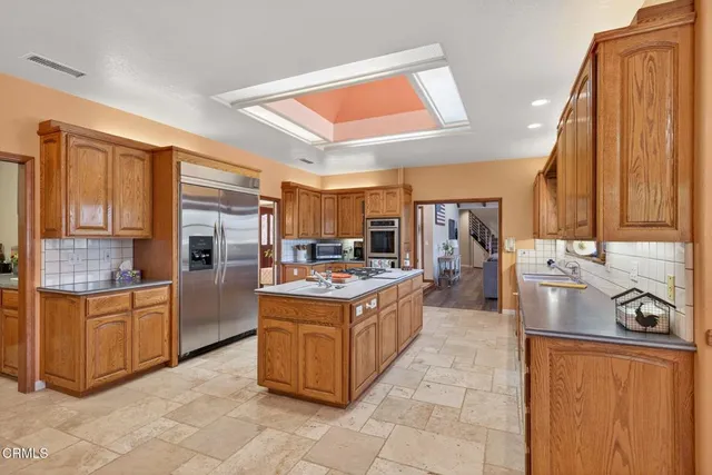 a kitchen with stainless steel appliances granite countertop a dining table and chairs