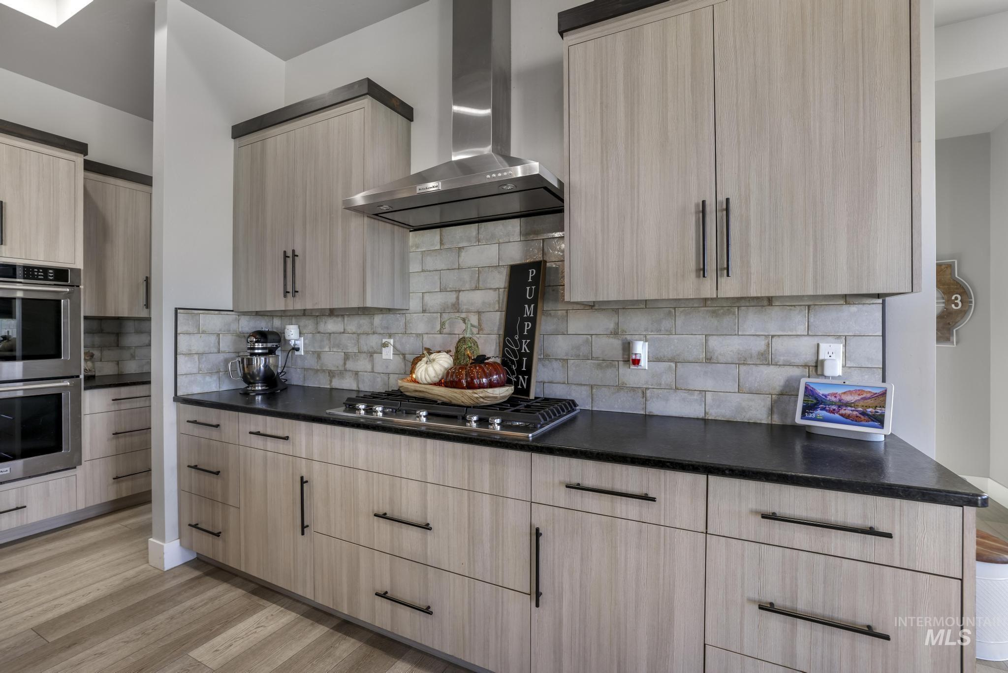 439 Meadowview Lane Twin Falls, ID 83301 - Photo 13 of 48 Kitchen featuring light brown cabinetry, wall chimney range hood, appliances with stainless steel finishes, light wood-style flooring, and modern cabinets