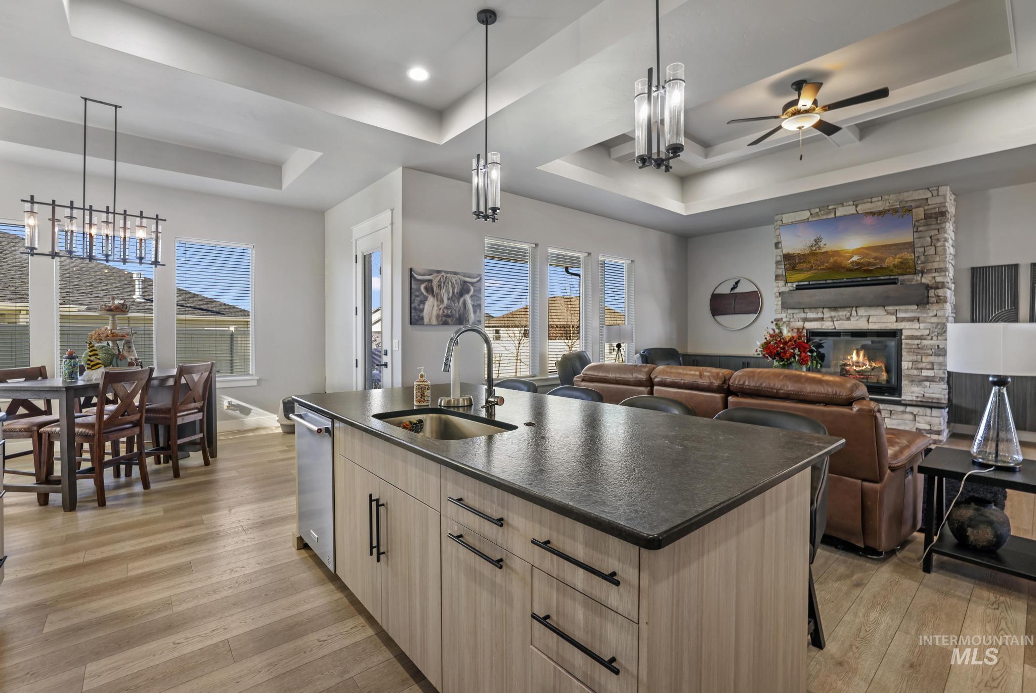 439 Meadowview Lane Twin Falls, ID 83301 - Photo 14 of 48 Kitchen featuring light wood-style floors, a tray ceiling, a center island with sink, and a fireplace