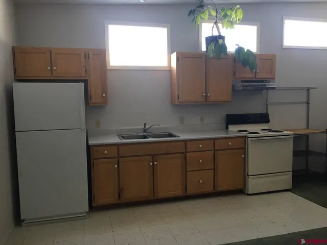 a kitchen with cabinets a window and refrigerator