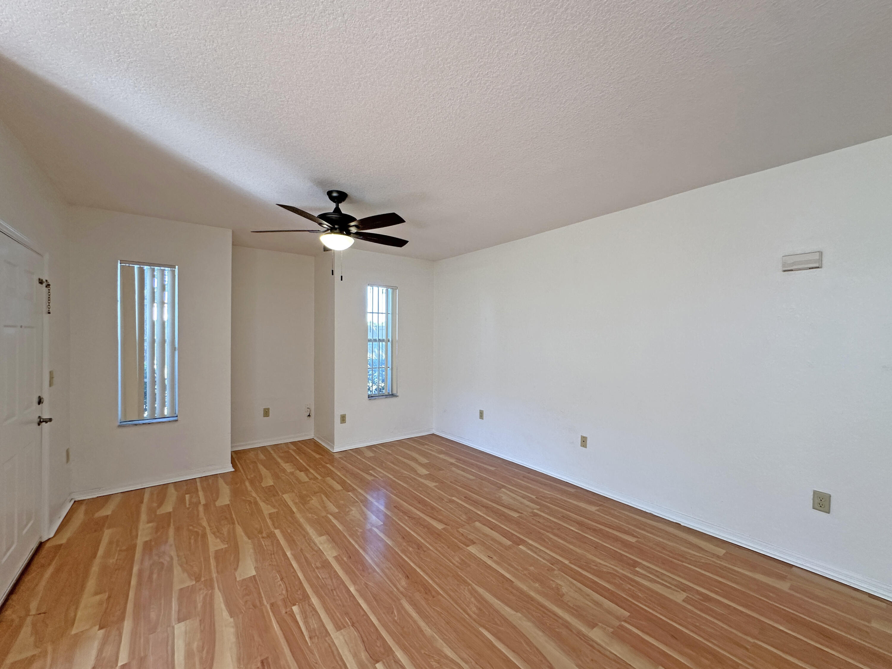 166 Southwest Peacock Boulevard, Unit 104 Port St. Lucie, FL 34986 - Photo 5 of 45 a view of empty room with wooden floor and fan