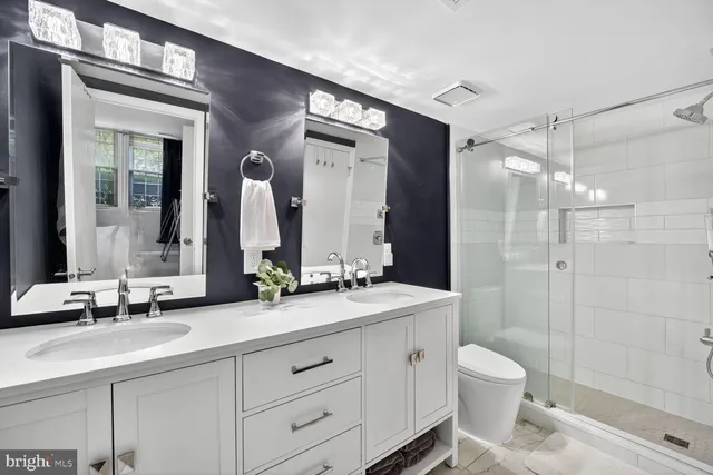 a bathroom with a double vanity sink toilet mirror and shower