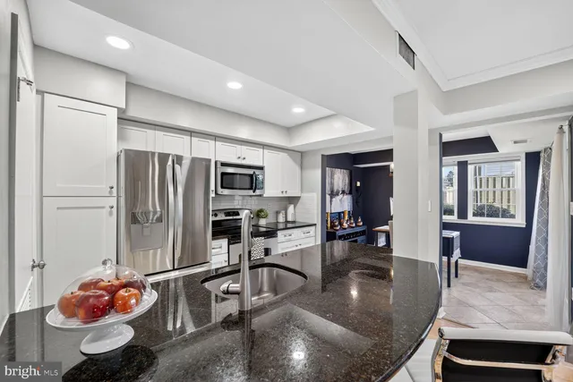 a kitchen with stainless steel appliances granite countertop a stove refrigerator and cabinets