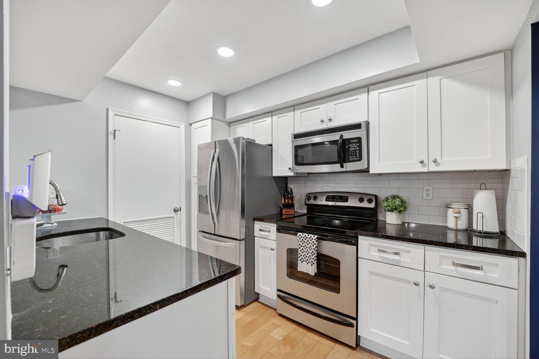 4519 28th Road South, Unit A Arlington, VA 22206 - Photo 3 of 33 a kitchen with stainless steel appliances granite countertop a refrigerator a stove a sink and white cabinets with wooden floor