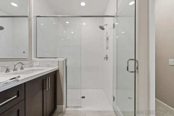 a bathroom with a granite countertop shower sink and mirror