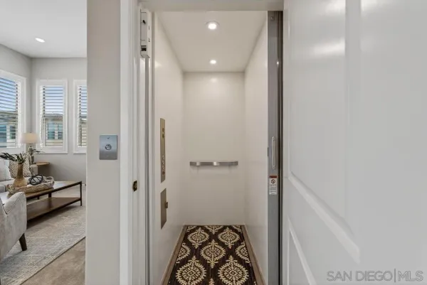 a view of a hallway with a livingroom with furniture and windows