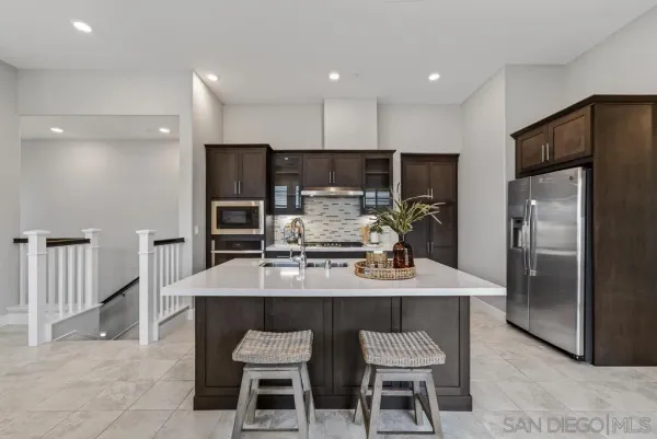 a kitchen with kitchen island a refrigerator stove a sink and chairs