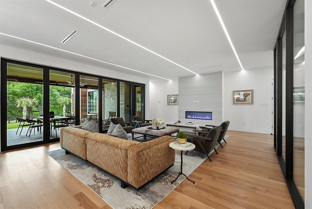 9457 Waterview Road Dallas, TX 75218 - Photo 10 of 25 Spacious living area featuring wood-finish flooring, a linear electric fireplace with a textured surround, and recessed linear ceiling lighting