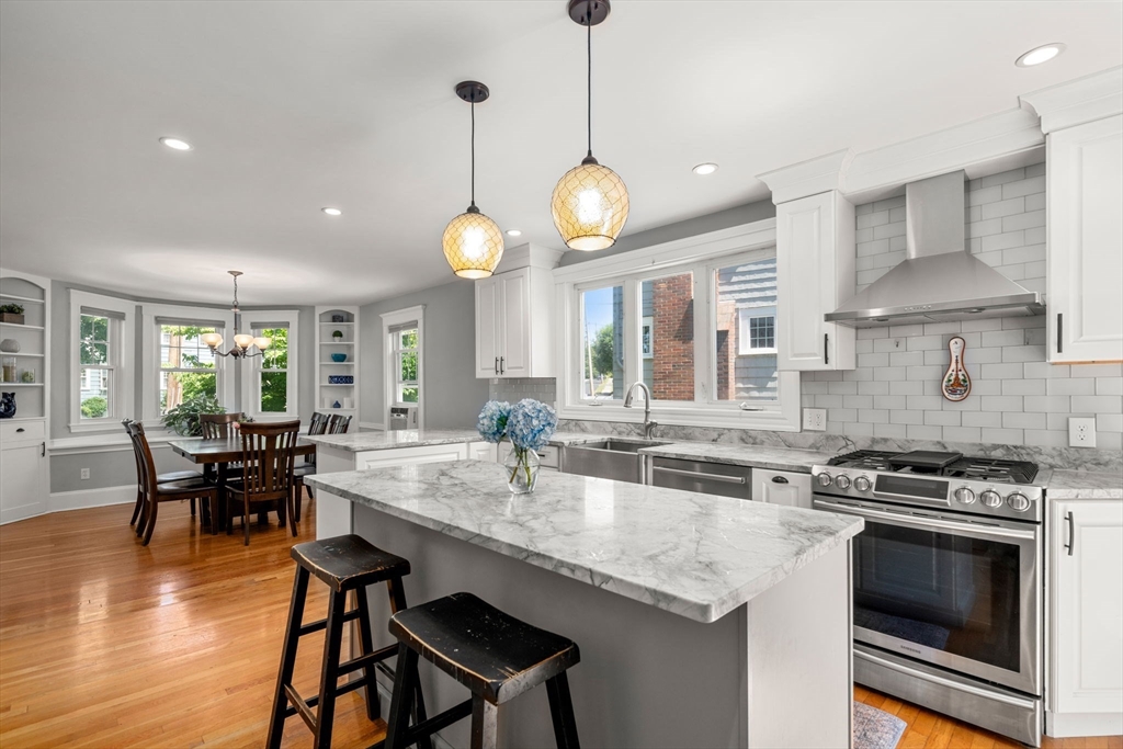 27 Frothingham Street Milton, MA 02186 - Photo 11 of 32 a kitchen with stainless steel appliances granite countertop a stove a sink a dining table and chairs with wooden floor