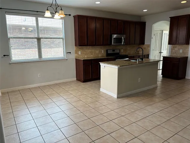 a kitchen with granite countertop a stove a sink and a microwave