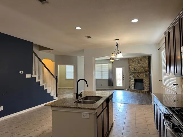 a kitchen with stainless steel appliances granite countertop a sink dishwasher a stove and a dining table with wooden floor