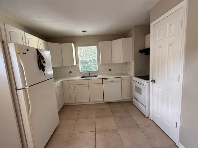 a kitchen with white cabinets and white appliances