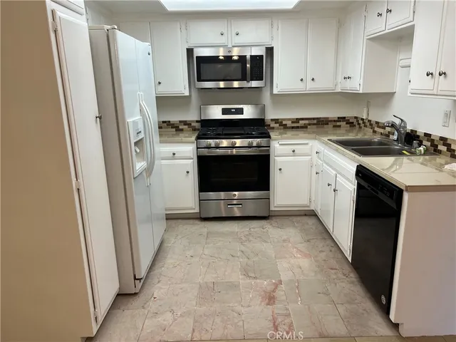 a kitchen with stainless steel appliances granite countertop a stove a sink and a refrigerator