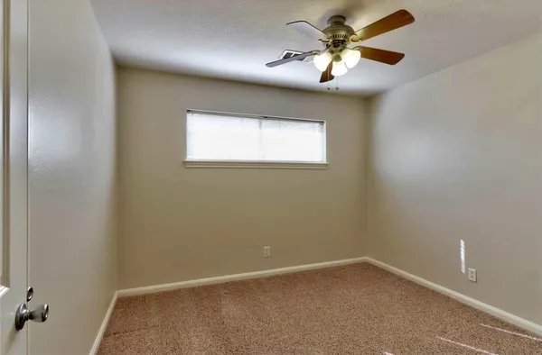 an empty room with a window and a fan