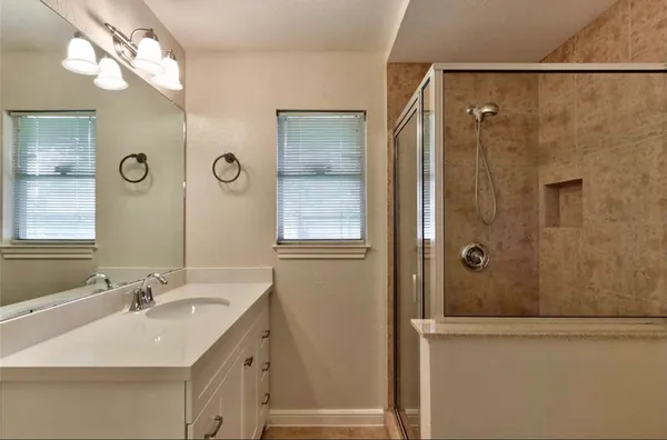 a bathroom with a double vanity sink a mirror and shower