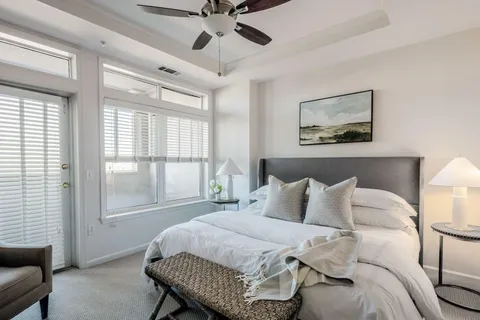 a bedroom with a bed painting on wall and a large window