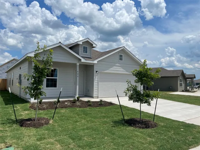 a small yard in front of the house with a bench