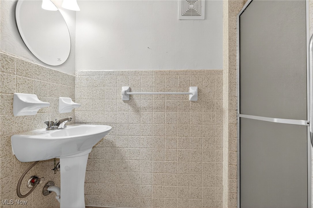 1806 Empire Road Wickliffe, OH 44092 - Photo 24 of 35 Full bath featuring tile walls, a shower stall, and a wainscoted wall