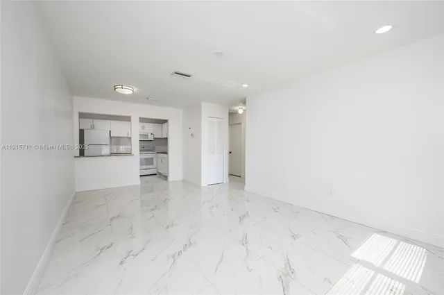 an empty room with kitchen view and wooden floor