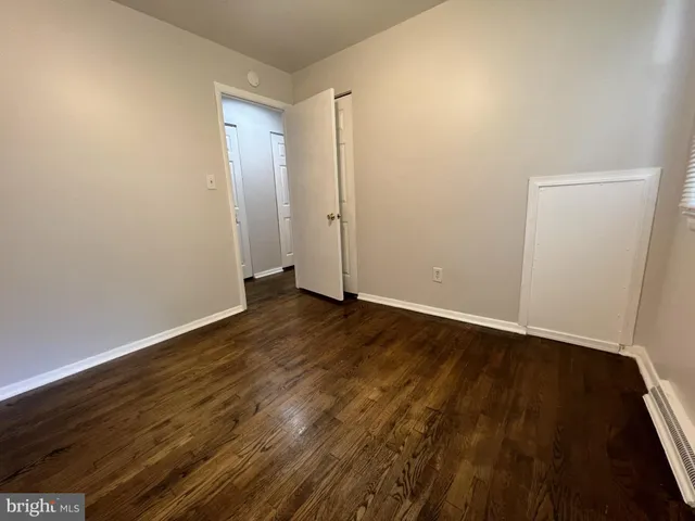 a view of an empty room with wooden floor and closet