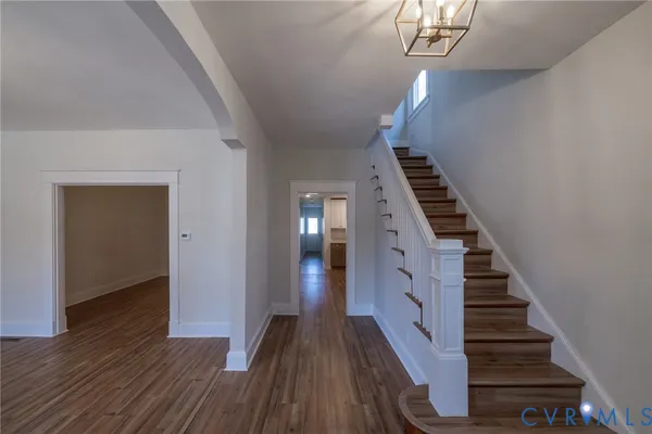 an empty room with wooden floor fireplace and windows
