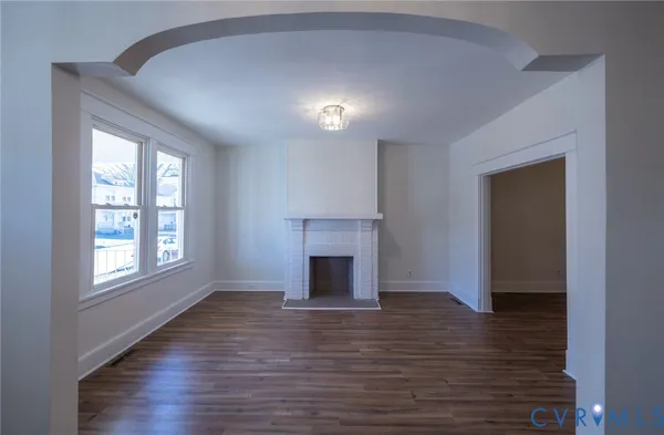 an empty room with wooden floor a fireplace and windows