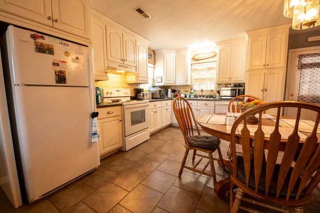 a kitchen with stainless steel appliances granite countertop a refrigerator a stove a sink dishwasher and white cabinets with wooden floor