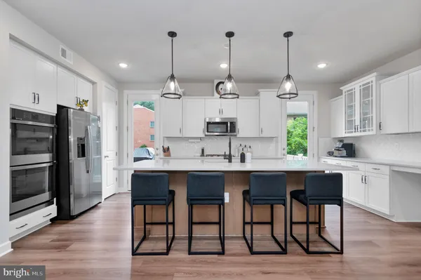 a open kitchen with stainless steel appliances granite countertop a sink a stove a refrigerator and island with wooden floor