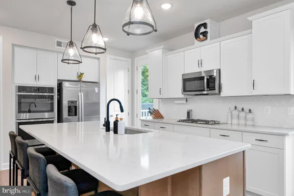a kitchen with stainless steel appliances kitchen island a white cabinets and wooden floor